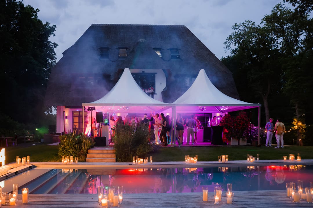 Avondfeest met twee verlichte pagodetenten en kaarsen langs het zwembad