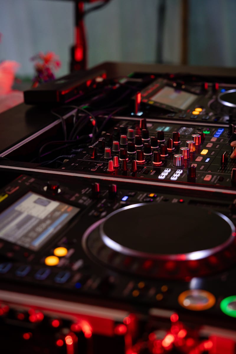 Close-up van een CDJ-speler en mixer in rood licht