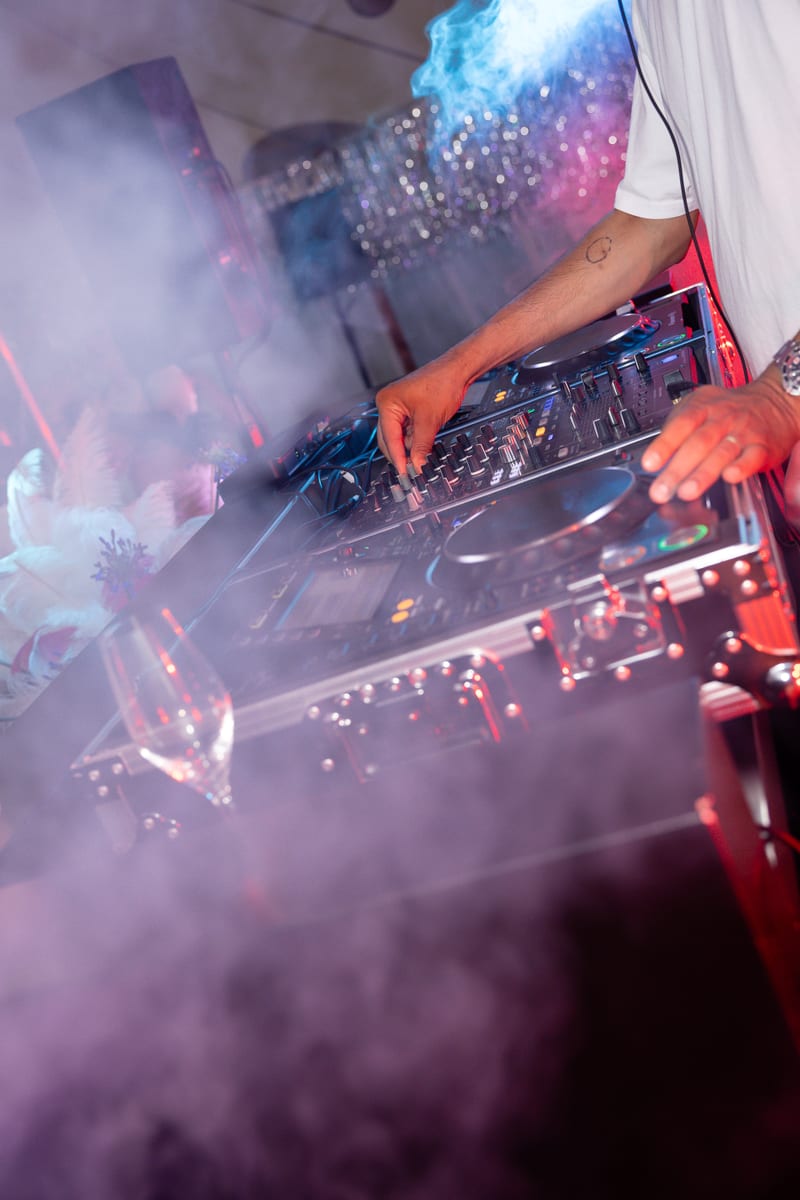 Handen van de DJ op de mixer, met rook en licht