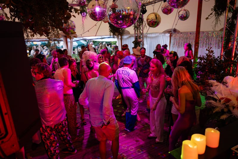 Volle feesttent met discoballen en roze uplights